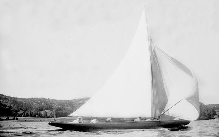En kappseglingsbåt passerar det lilla samhället Sunningen vid Byfjordens utlopp nära Uddevalla. Bilden är tagen den 30 juli 1899 klockan två på eftermiddagen. Fotograf: Henry Thorburn. 