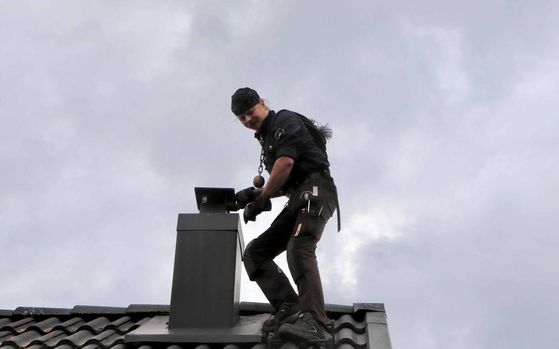 Johan traskar vant över takpannorna för att nå fram till skorstenen. Sotarna har ingen säkerhetsutrustning på sig uppe på taken. 