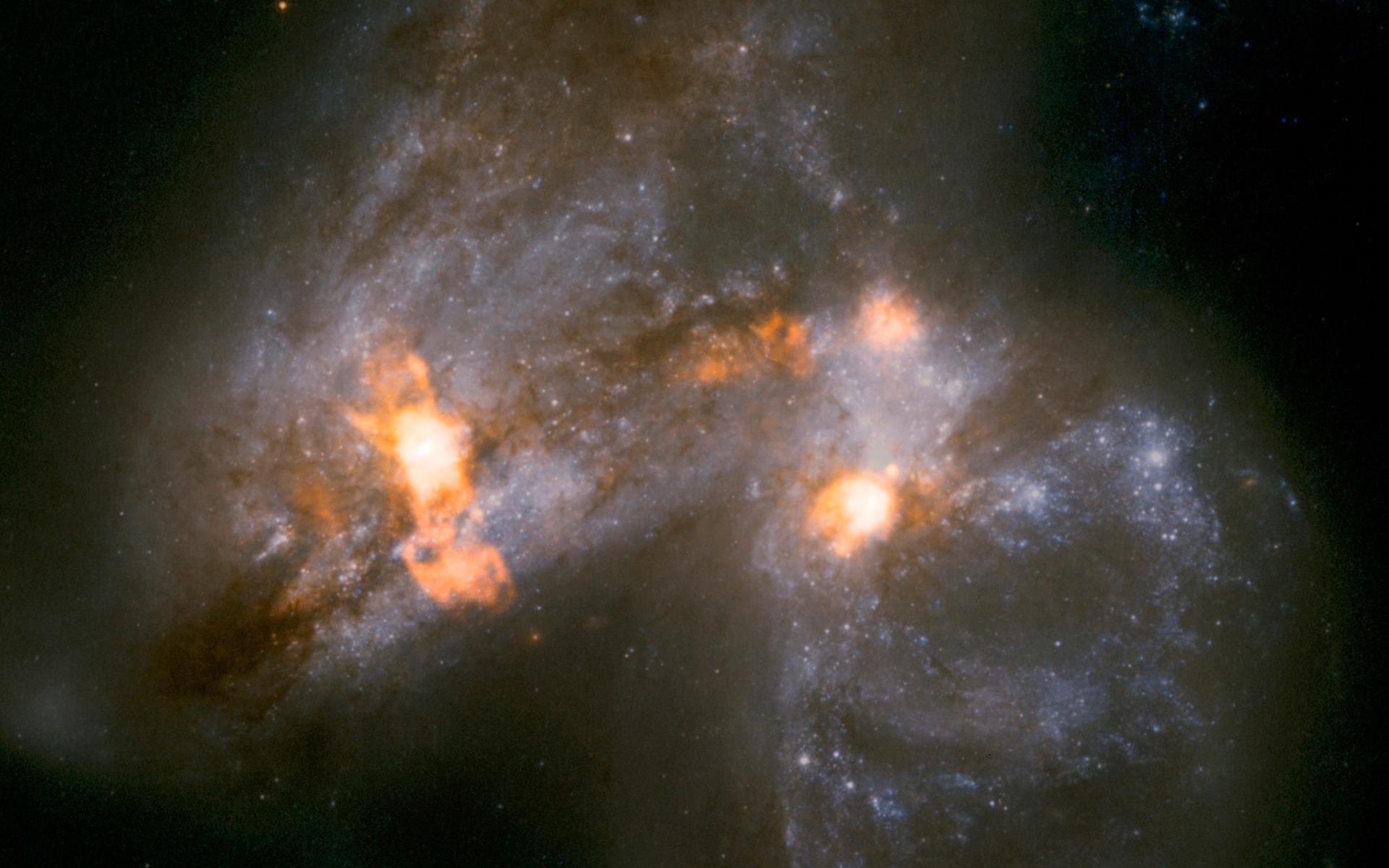 Galaxparet Arp 299 håller på att smälta samman. Lofar avslöjar hur vindar lika stora som en galax blåser ut från en jättelik stjärnfabrik – triggat av krocken mellan galaxerna – som ligger dold bakom lager av stoft och damm i galaxernas ena kärna. Foto: Ramirez-Olivencia/NASA/ESA.
