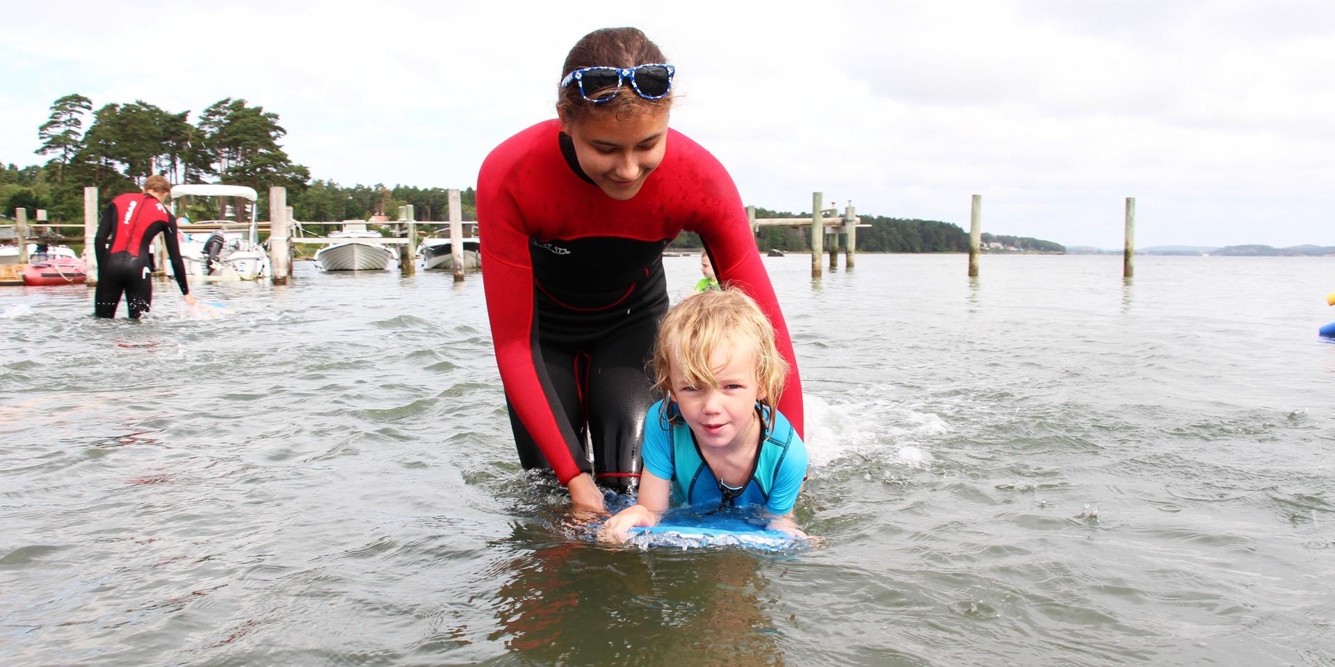 Axel Härsjö, fem år, får hjälp av simläraren Isa Simonsson att ta sig fram med flytplattan.
