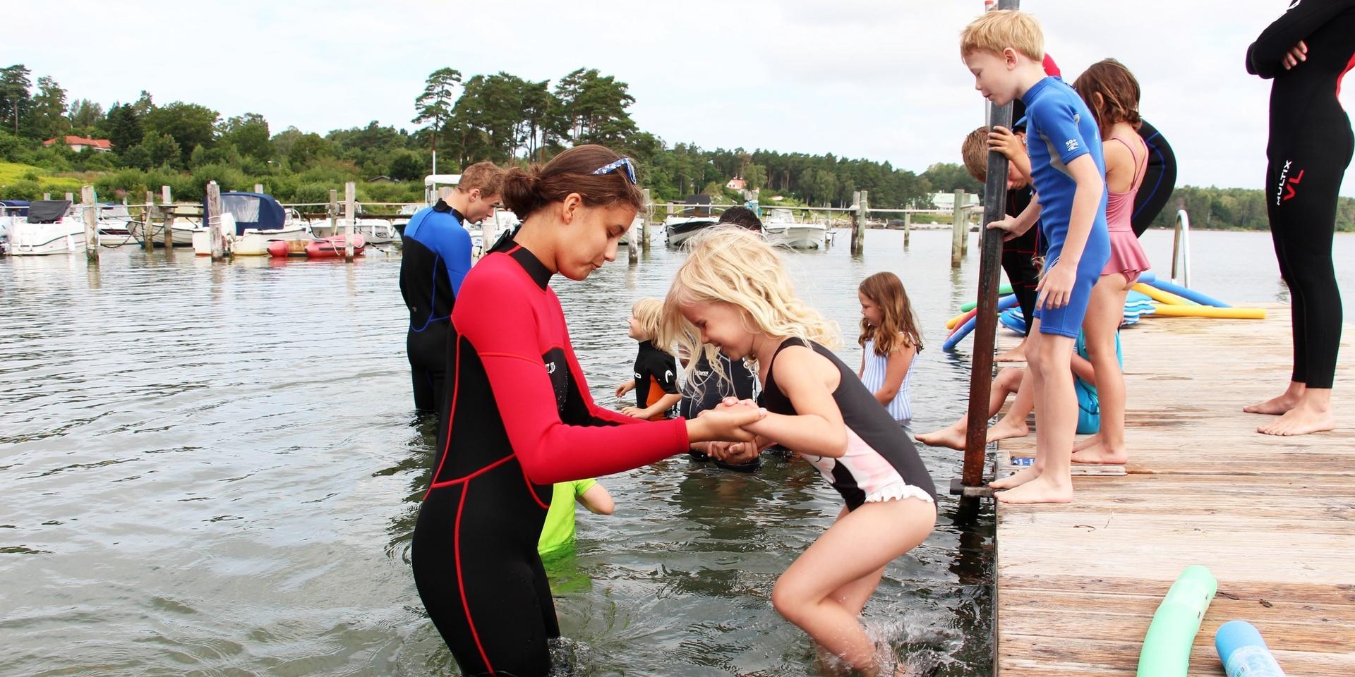 Freja Bertén Gustavsson, sex år, får hjälp av Isa Simonsson att hoppa ner i vattnet.