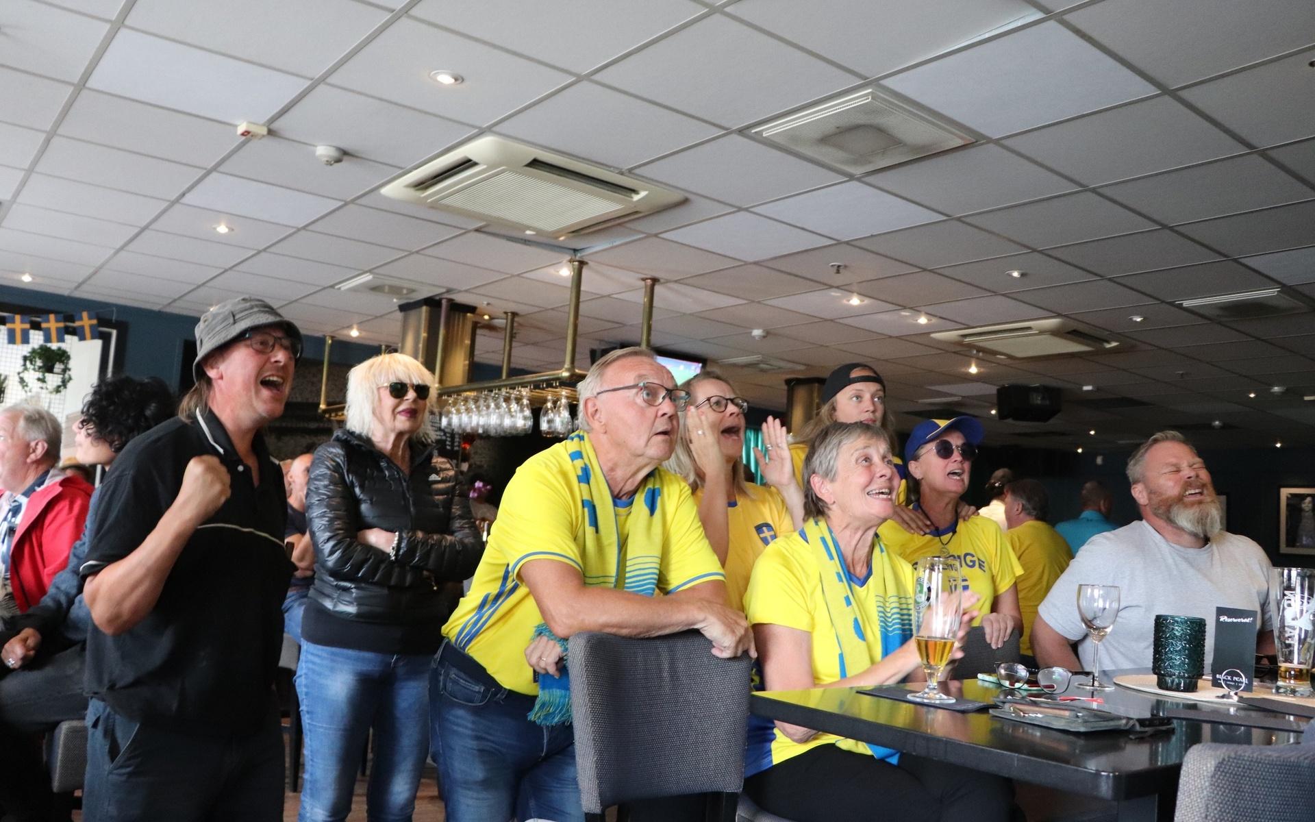 Fler personer ansluter till Rolfö-fansens bord. ett högt ”JAAAA” utrbrister när en av de svenska straffskyttarna gör mål. 