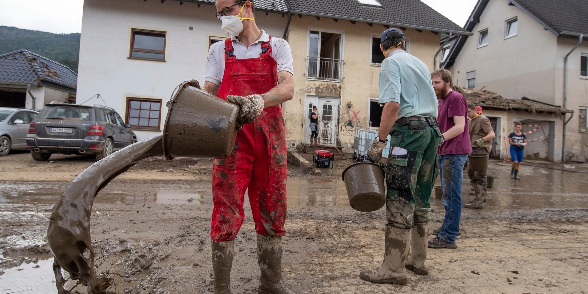 Frivilliga i Altenahr i Tyskland bildar en mänsklig kedja och langar undan lera och vatten.